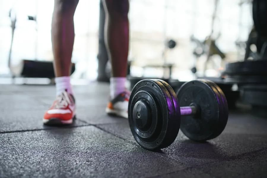 A hand lifting a dumbbell from the rack